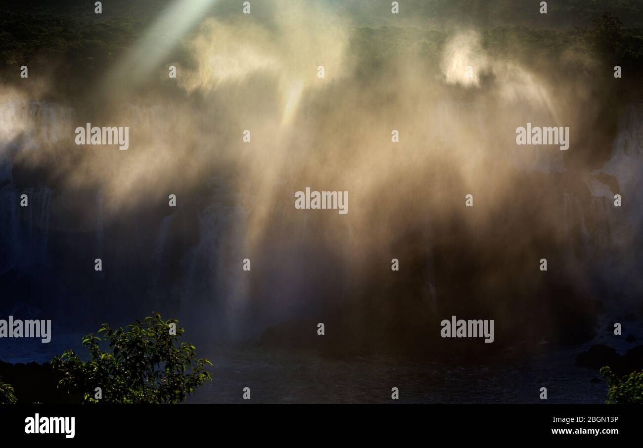 Abendsonne, die Lichtstrahlen durch den Nebel an den Iguacu Wasserfällen, Brasilien, Südamerika verursacht Stockfoto