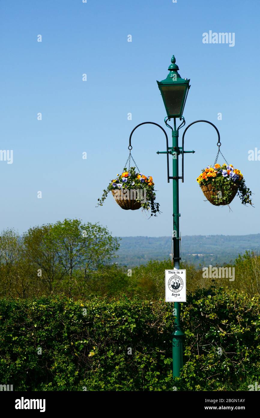 Hängende Körbe an Straßenlampe mit Nachbarschaftsüberwachung Schild und Blick über Medway Tal nach North Downs, Bidborough Ridge, Kent, England Stockfoto