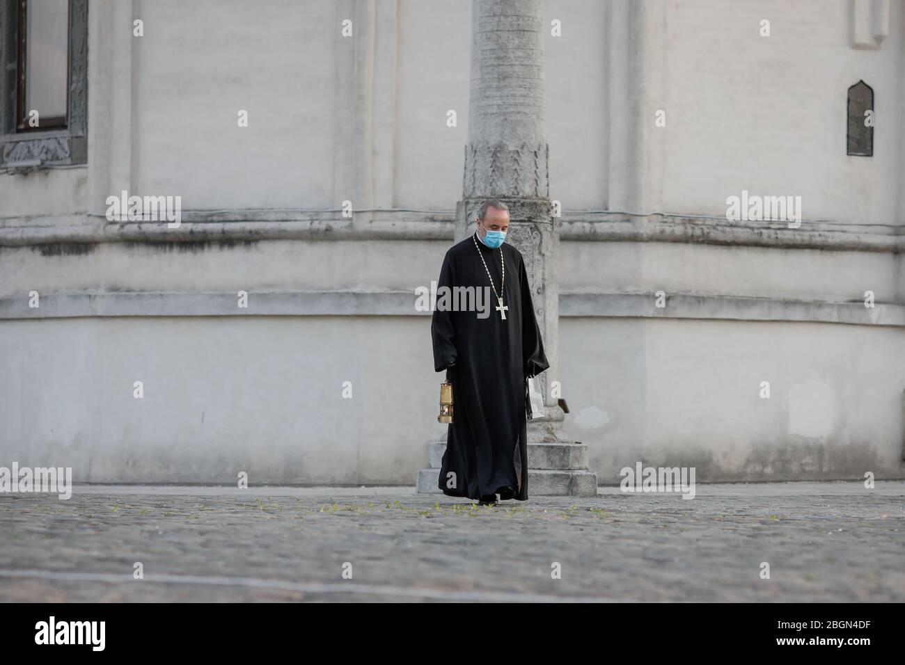 Bukarest, Rumänien - 18. April 2020: Ein orthodoxer christlicher Priester mit einer chirurgischen Maske wegen der COVID-19 Pandemie trägt das Heilige Licht während der Stockfoto