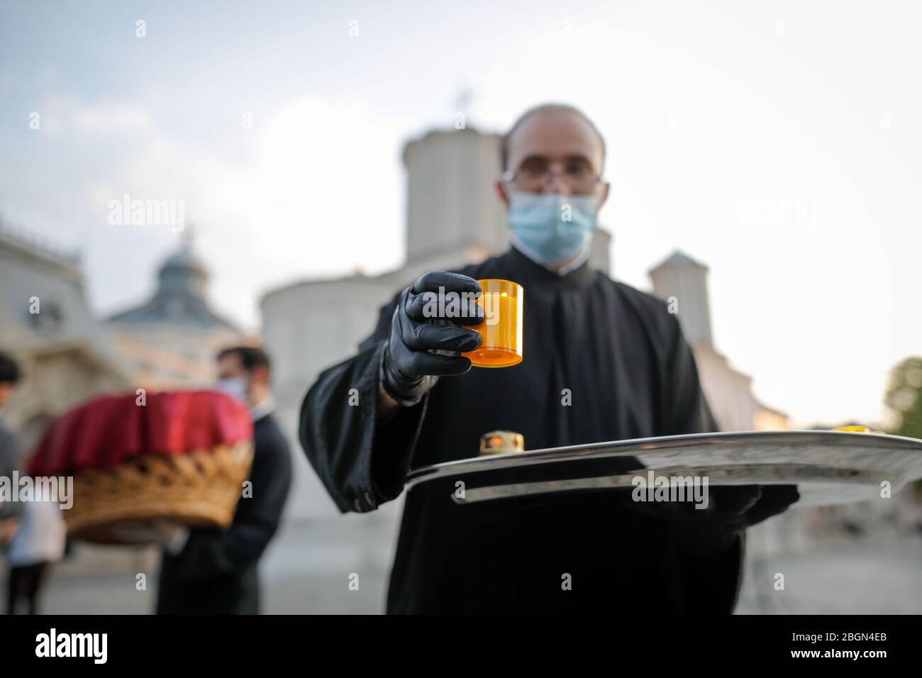 Bukarest, Rumänien - 18. April 2020: Ein orthodoxer christlicher Priester mit chirurgischer Maske wegen der COVID-19-Pandemie teilt das Heilige Licht während der OP Stockfoto