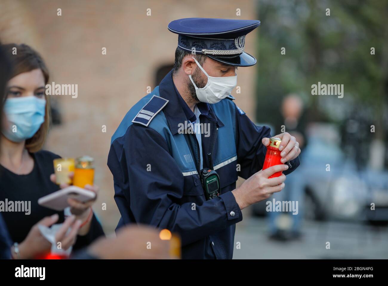 Bukarest, Rumänien - 18. April 2020: Rumänischer Polizist mit chirurgischer Maske wegen der COVID-19-Pandemie nimmt das Heilige Licht während der orthodoxen EAS Stockfoto