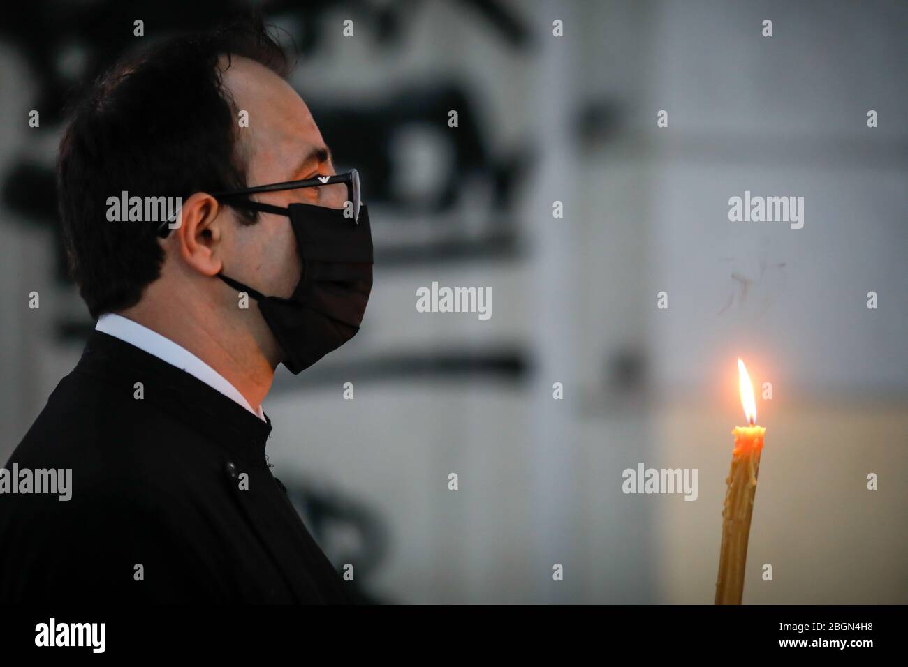 Bukarest, Rumänien - 18. April 2020: Ein orthodoxer Priester, der Handschuhe und Maske trägt, wegen der Sperrung der COVID-19-Pandemie, liefert das Heilige Licht während der Zeit Stockfoto