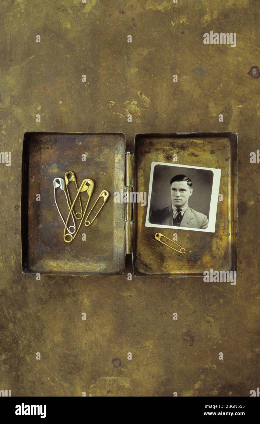 Vintage Messing Box mit gebrauchten Sicherheitsnadeln und schwarz-weiß Studio Foto des jungen Mannes der 1940er Jahre Stockfoto