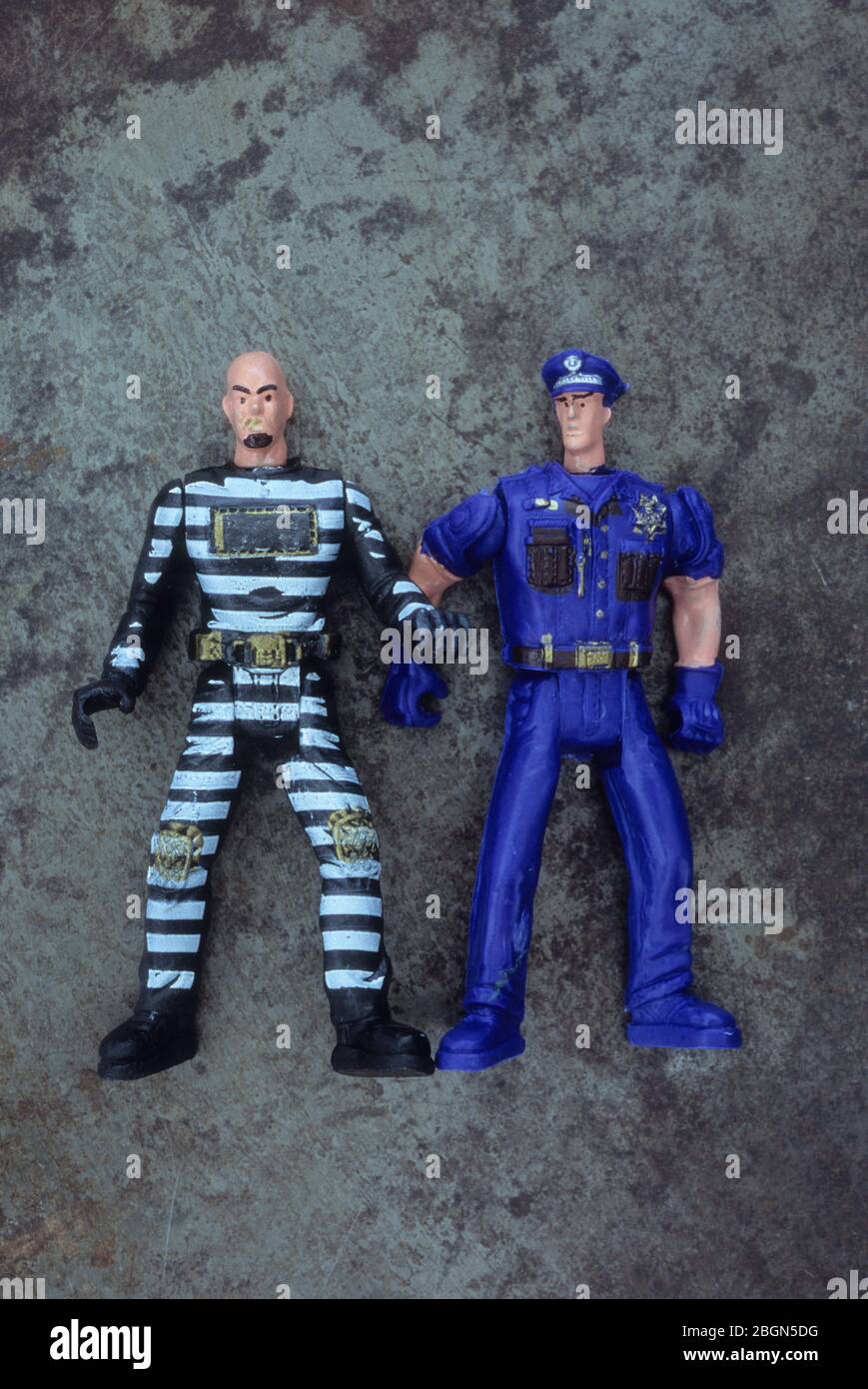 Plastikspielzeug-Modelle des amerikanischen Art Polizeibeamten mit finster aussehenden Verbrecher im gestreiften Jumpsuit Stockfoto