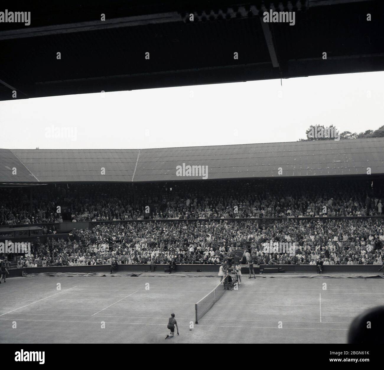 1950er Jahre, historisch, Wimbledon, Blick aus dieser Ära des Centre Court, voller Zuschauer, im berühmten Wimbledon Lawn Tennis Club, London, England, Großbritannien. Die Ursprünge des Tennisspiels in wimbledon gehen auf die Entscheidung des All England Croquet Club zurück, einen seiner Rasenflächen für den neuen Tennissport zu verwenden. was sich als populär erwies, dass der Verein seinen Namen änderte, um das Wort Tennis aufzunehmen und 1877 eine Meisterschaft auszutragen. Stockfoto