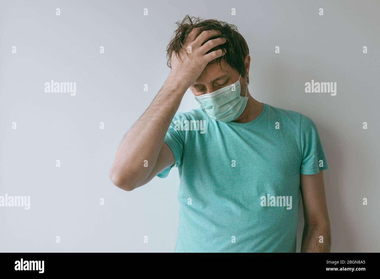 Mann mit Maske mit Migränekopfschmerzen als Covid-19-Symptome, Porträt einer männlichen Person mit Virusinfektion während Pandemien Stockfoto