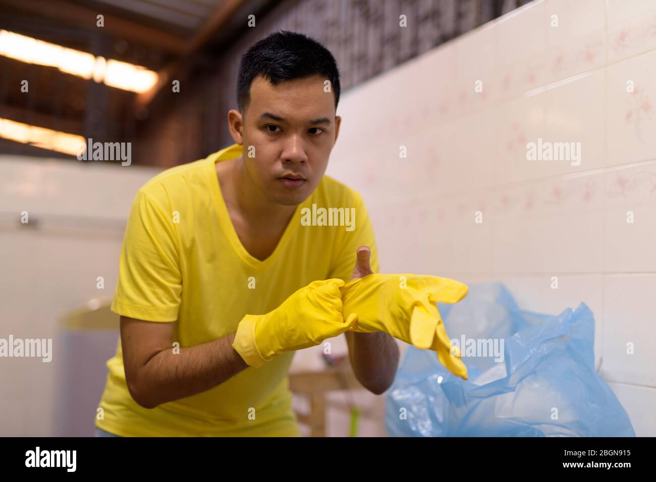 Porträt des jungen asiatischen Mann mit Handschuhen während Hausarbeiten zu tun Stockfoto