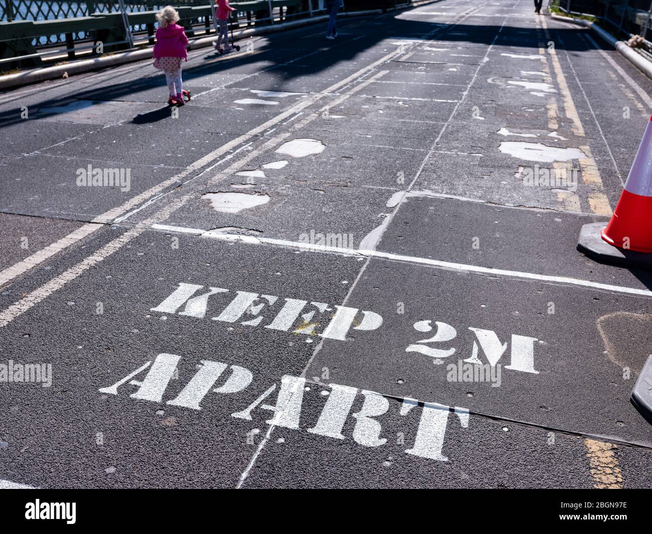 5. April 2020 EIN Schild auf der Fahrbahn warnt Fußgänger, sich fernzuhalten, um die Ausbreitung des Covid-19-Virus zu verhindern. Zwei junge Stockfoto