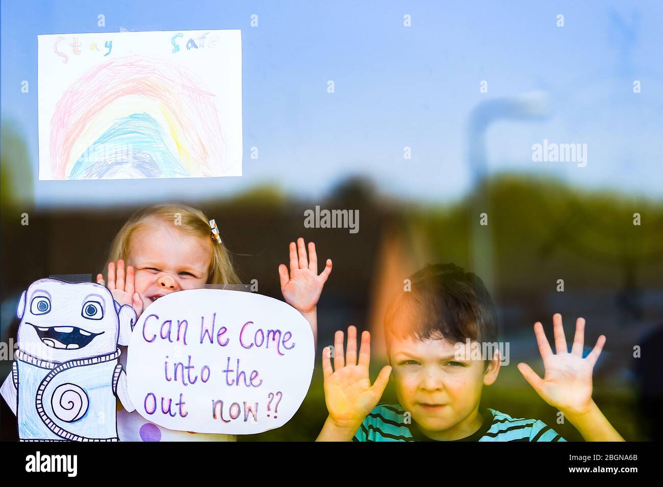 Droitwich, Worcestershire, Großbritannien. April 2020. Der 7-jährige will Keight erscheint mit seiner jungen Schwester Orla, 2, am Fenster ihres Hauses in Droitwich Spa mit den Plakaten, die sie für den Welttag und das NHS gemacht haben. [Anmerkung: Elterliche Erlaubnis erteilt] Quelle: Peter Lopeman/Alamy Live News Stockfoto