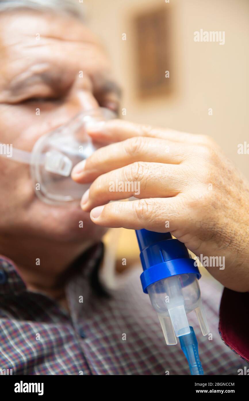 Leitender Mann, der medizinische Geräte für die Inhalation mit Atemschutzmaske verwendet, Vernebler im Zimmer Stockfoto
