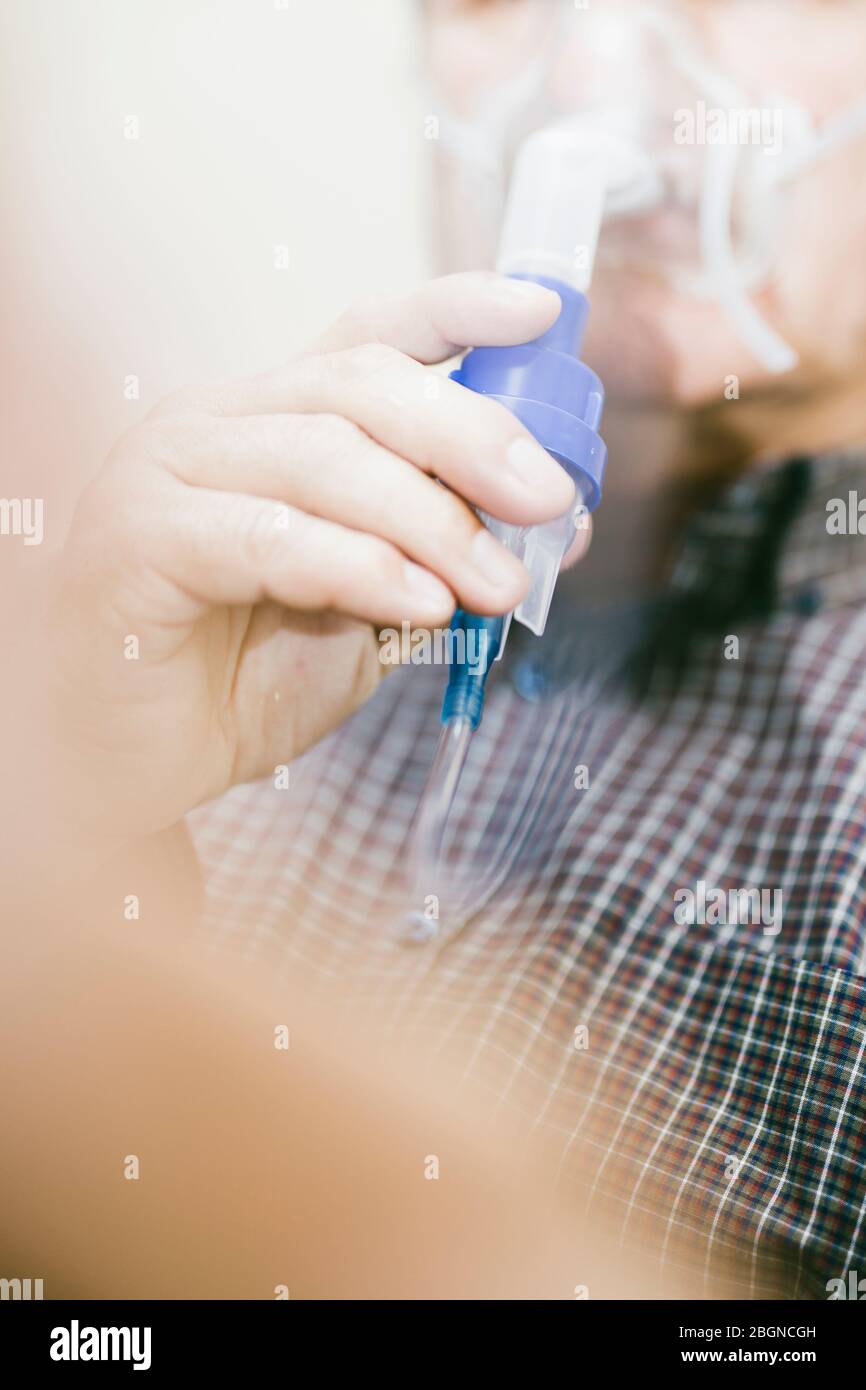 Leitender Mann, der medizinische Geräte für die Inhalation mit Atemschutzmaske verwendet, Vernebler im Zimmer Stockfoto