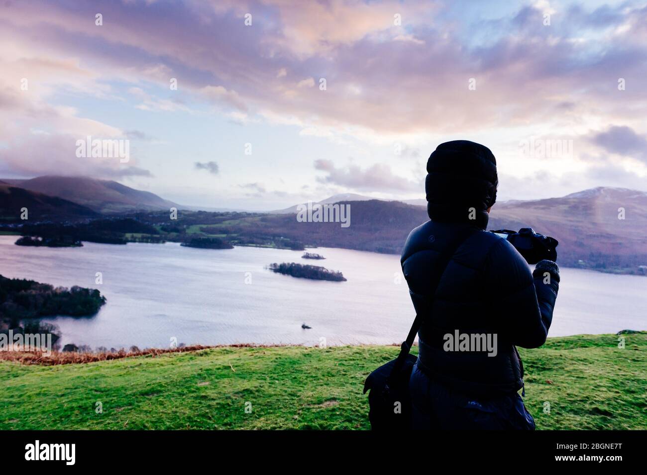 Ein Fotograf hat sich warm in eine Daunenjacke gewickelt und fotografiert den Blick über den Derwent Water Catgells Gipfel mit Blick auf Derwent Water in the Lakes Stockfoto