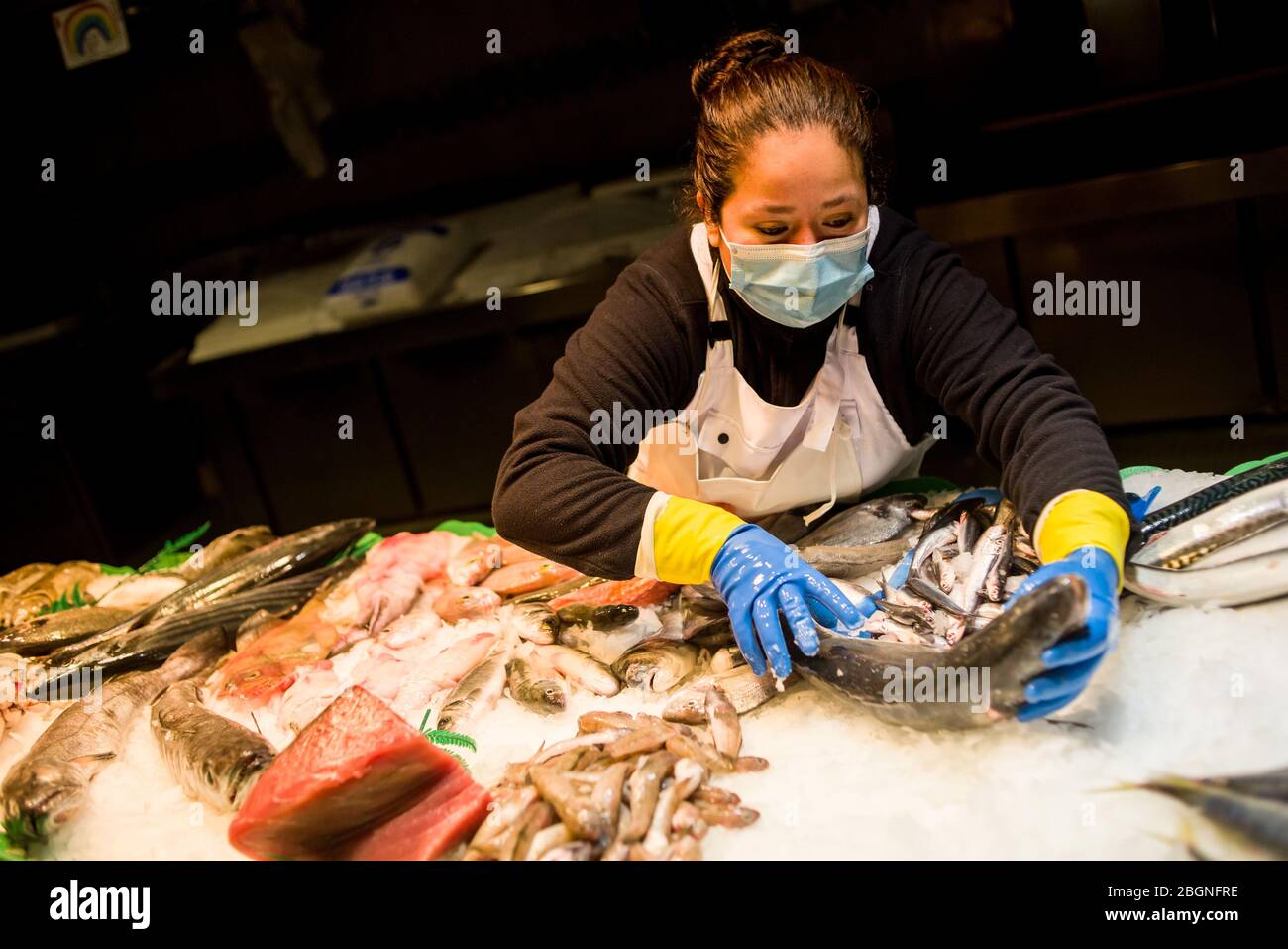 22. April 2020, Barcelona, Katalonien, Spanien - EINE Frau mit einer schützenden Gesichtsmaske bereitet seinen Fischerstall am frühen Morgen auf dem La Boqueria Markt in Barcelona vor. Spanien wird mit der Deeskalation der Coronavirus-Maßnahmen beginnen, ohne das Auftreten der Epidemie zu kennen, stabilisieren sich die Sterbefälle des Coronavirus in den letzten 24 Stunden mit 435. Quelle: Jordi Boixareu/Alamy Live News Stockfoto