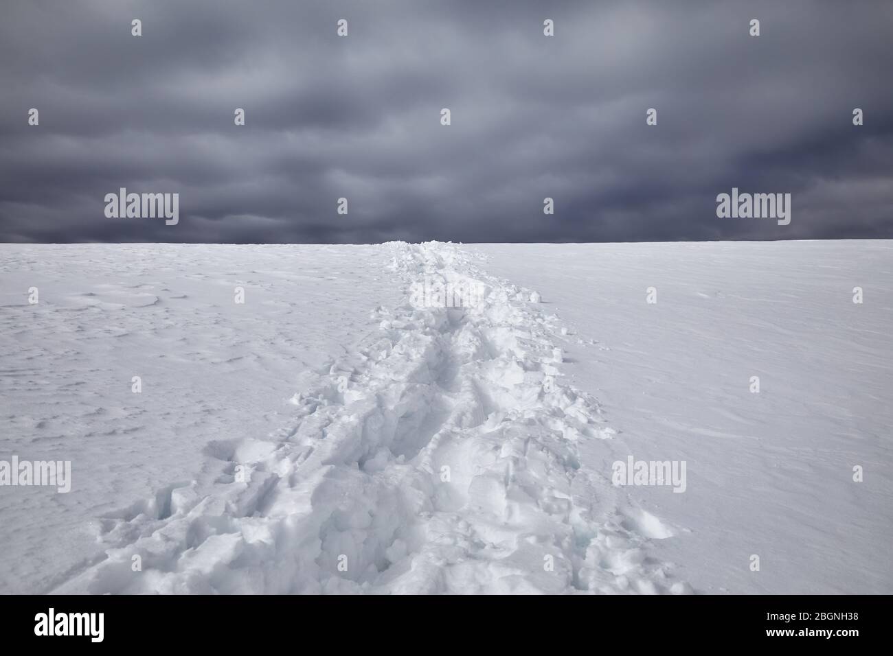 Fußabdrücke auf dem Schnee gegen dunkle bewölkten Himmel Hintergrund Stockfoto