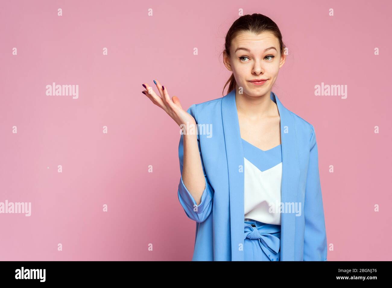 Ein verwirrtes Mädchen zuckelt. Ein Mädchen ist empörtbon der lila Hintergrund. Ein Mädchen mit erhöhten Augenbrauen. Stockfoto