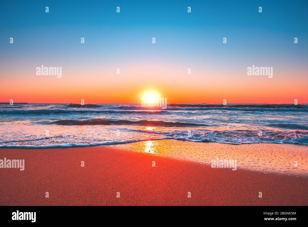 Sonnenaufgang oder Sonnenuntergang am Strand mit klarem blauen Himmel und aufgehender Sonne Stockfoto