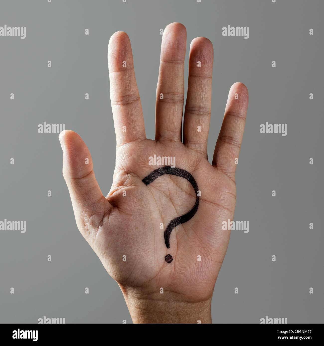 Nahaufnahme der Hand eines Mannes mit einem Fragezeichen in seiner Handfläche, auf einem grauen Hintergrund gemalt Stockfoto