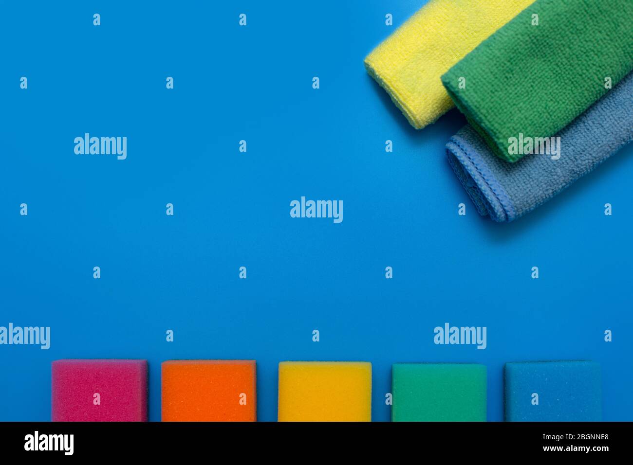 Drei bunte, trockene Mikrofasertücher und Regenbogenfarben für die Reinigung verschiedener Oberflächen in Küche, Bad und anderen Zimmern, auf einer blauen BA Stockfoto