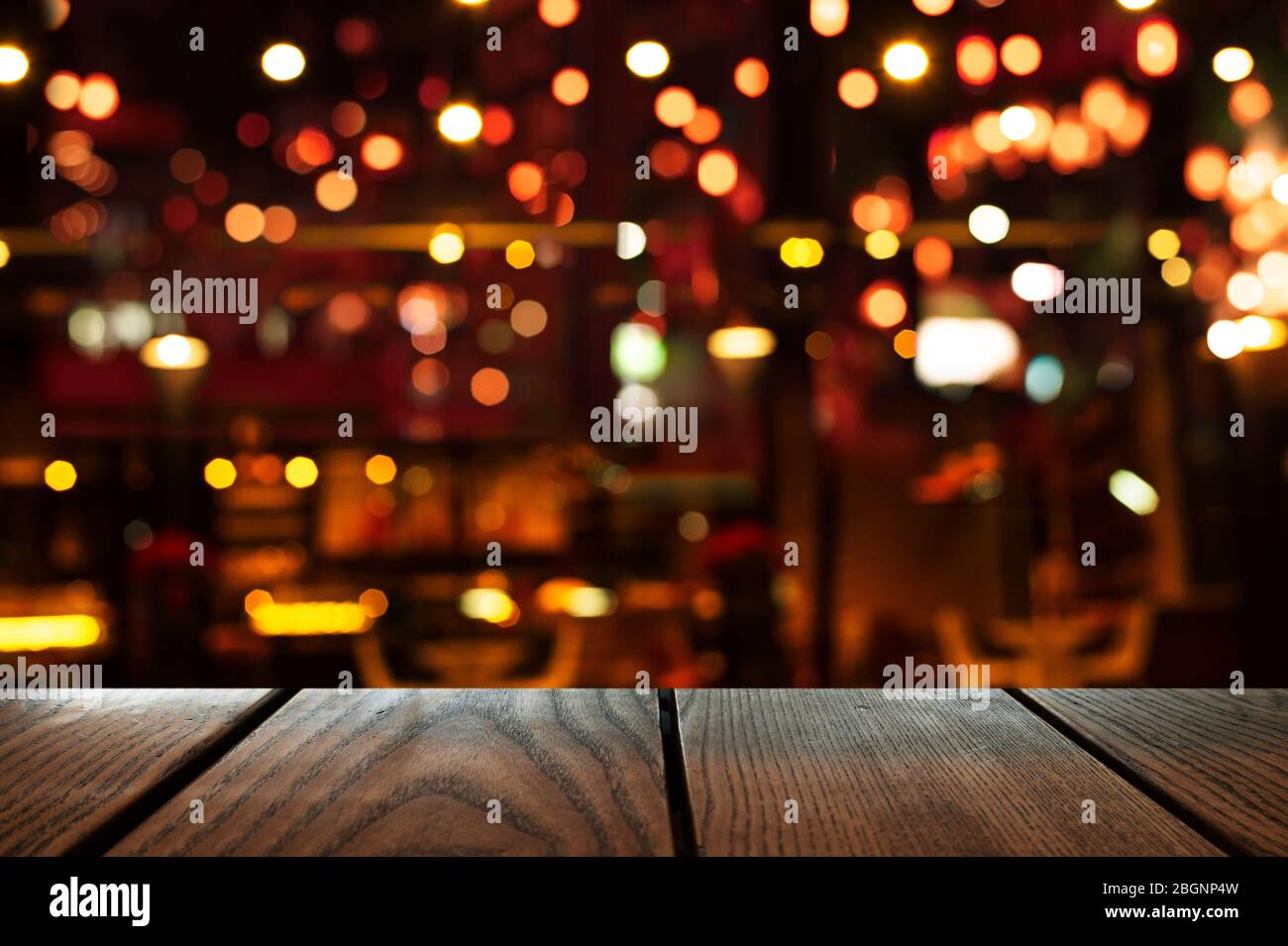 Blur Bokeh der Bar oder Club Party dunklen Nacht Licht Hintergrund mit Holz Tisch Hintergrund Stockfoto