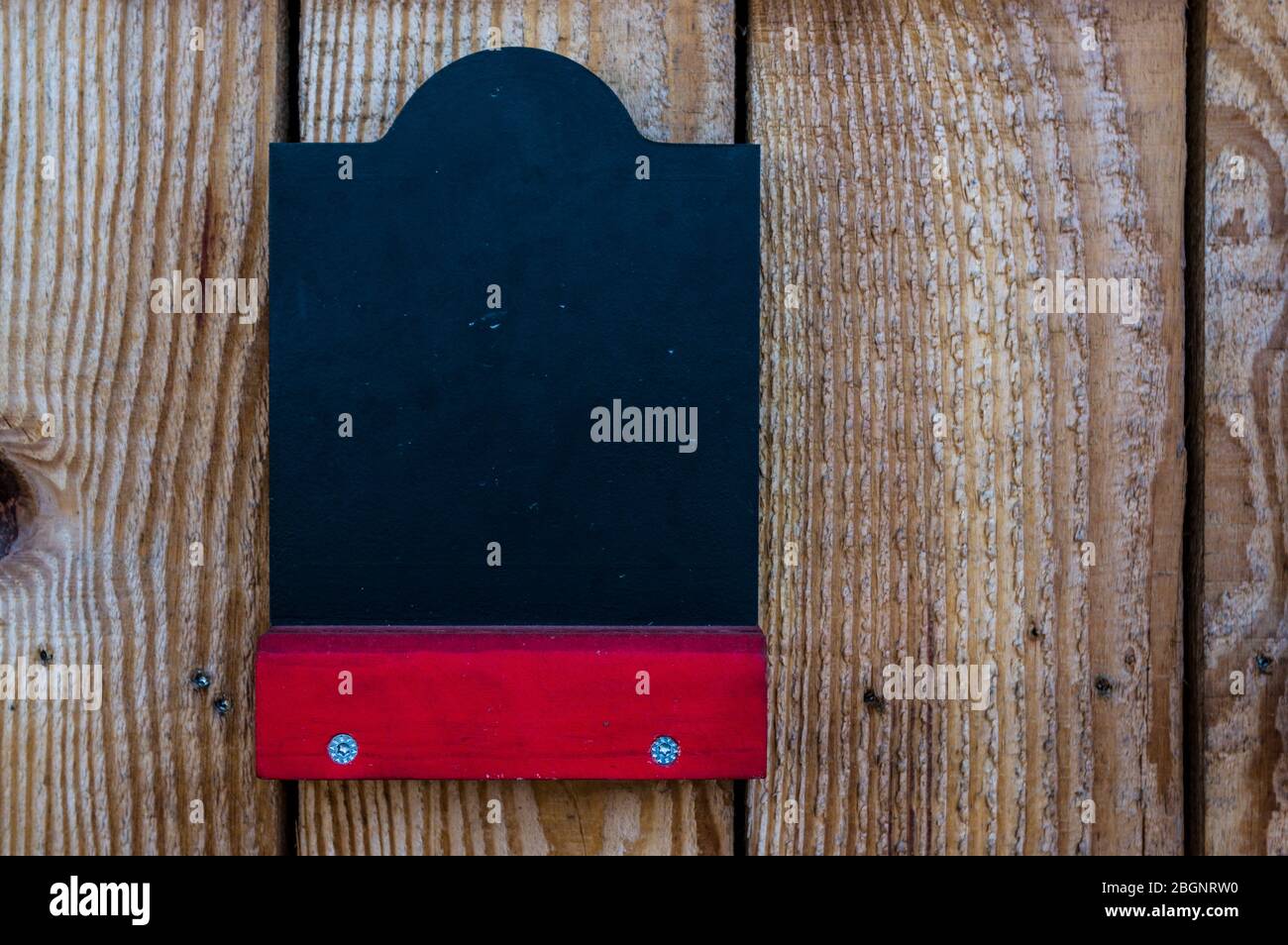 Leere Kreidetafel auf einem Holzstand mit rotem Regal für kostenlose Etikettierung Stockfoto