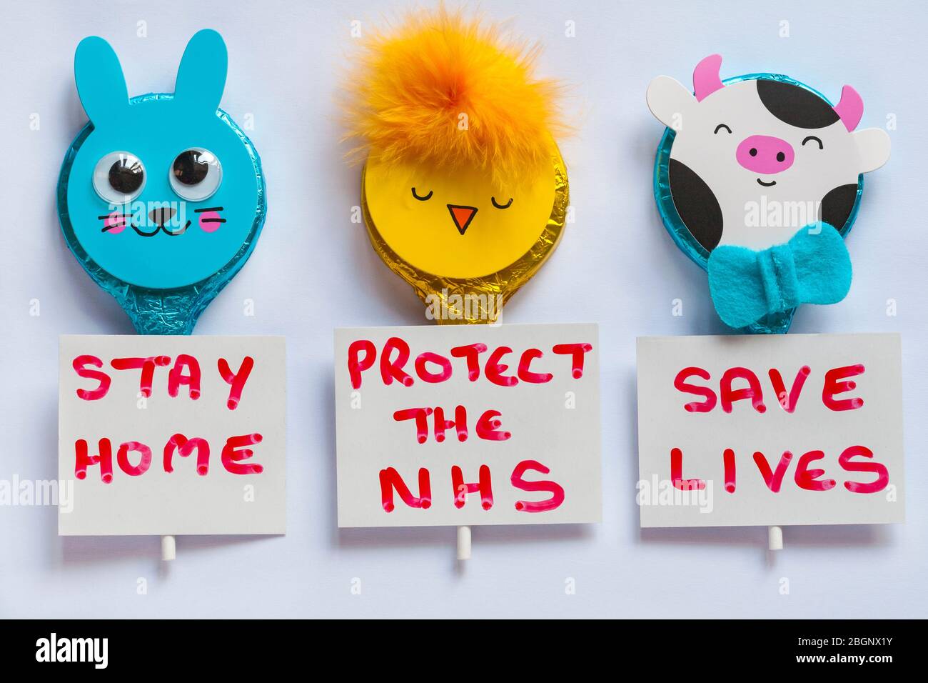 M&S Ostern Tiere Milchschokolade Lutscher mit Stay Home, schützen Sie die NHS, Save Lives Zeichen isoliert auf weißem Hintergrund - Coronavirus Sperrung UK Stockfoto