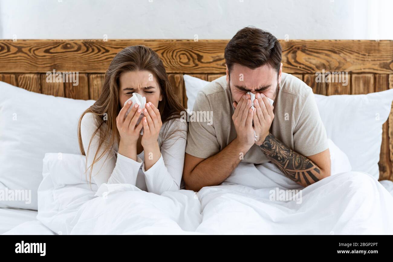 Paar im Bett wischen Nase mit Servietten Stockfoto