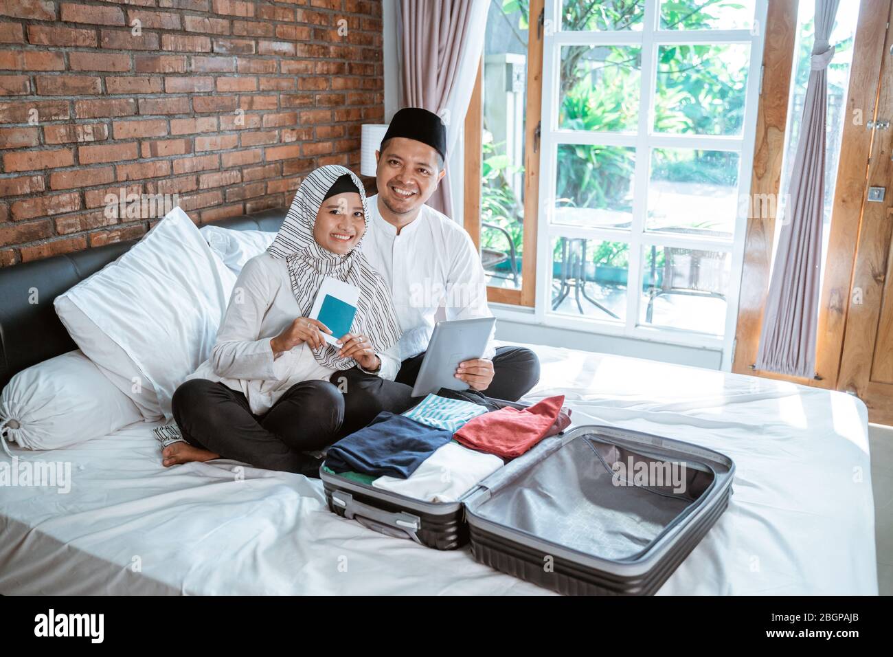 Glückliches Porträt von jungen muslimischen Paar mit Pass und Tablet-Verpackung für den Urlaub Stockfoto Glückliches Porträt von jungen muslimischen Paar mit Pass und Tablet-Verpackung für den Urlaub Stockfoto