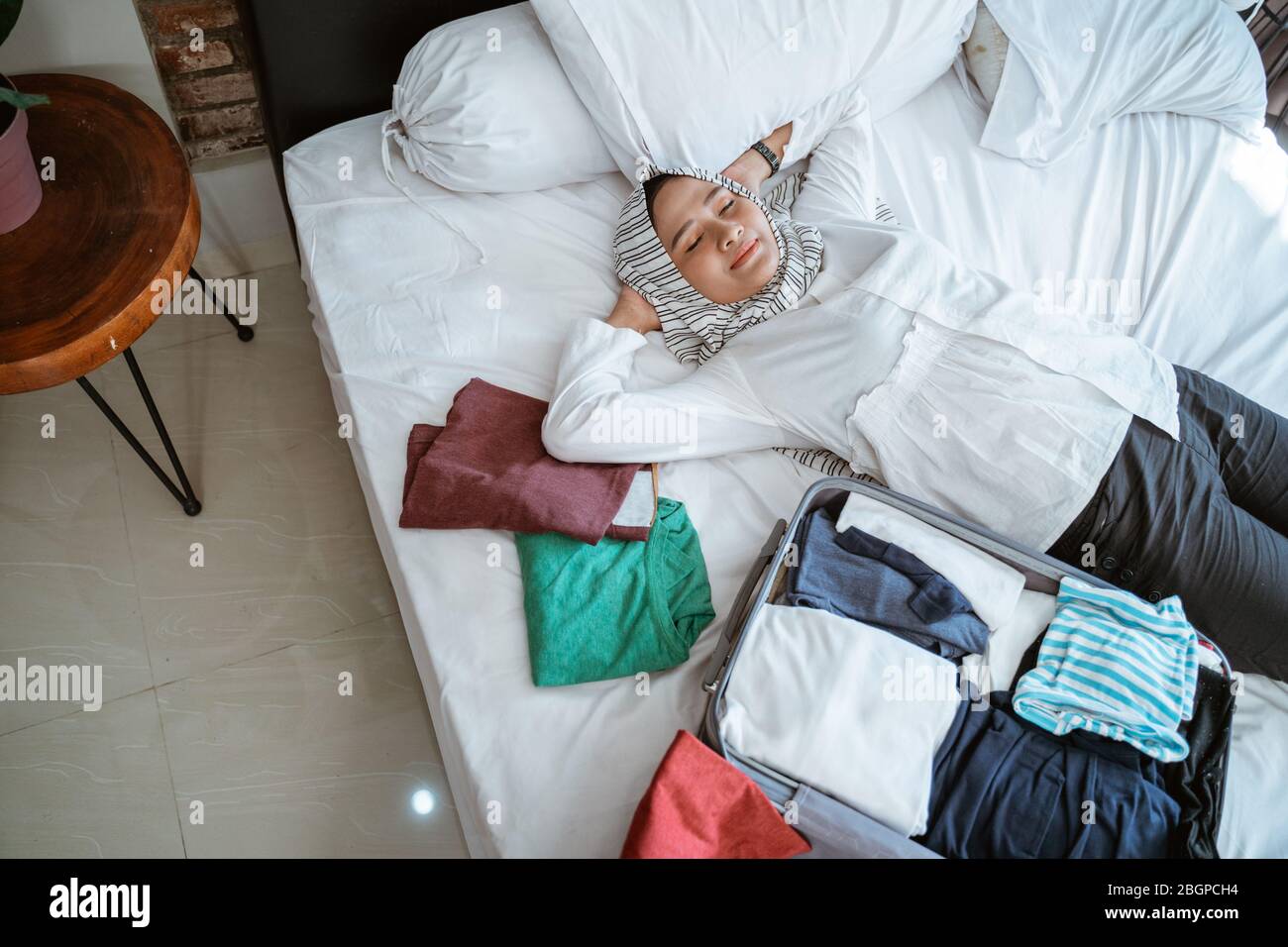 muslimische Frau mit Schal entspannen beim Packen zu Hause Stockfoto muslimische Frau mit Schal entspannen beim Packen zu Hause Stockfoto