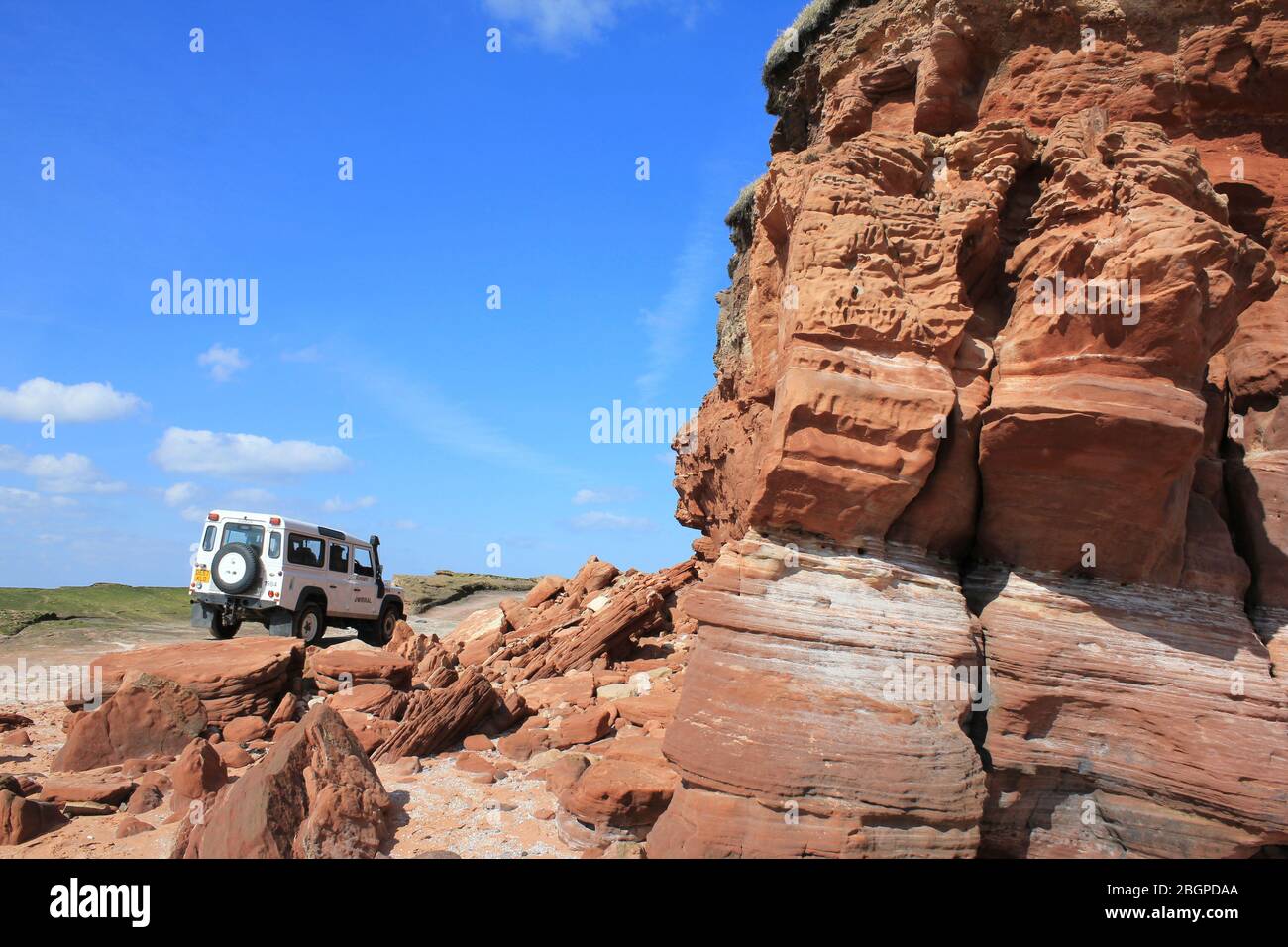 Wirral Rangers Landrover fährt an den Bunter Sandstone Cliffs von Hilbre Island, Wirral, Großbritannien vorbei Stockfoto