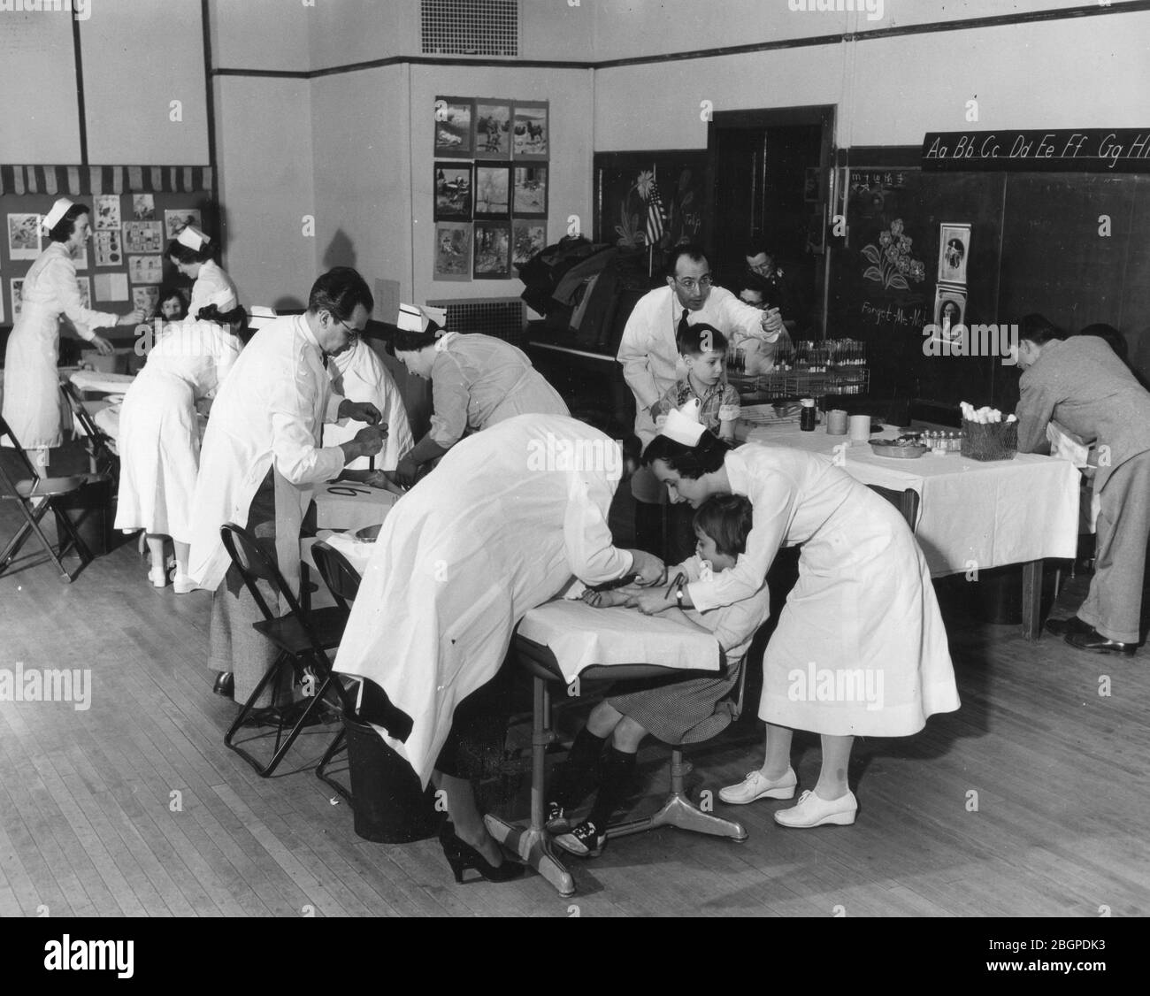 Kinder in einem Klassenzimmer erhalten während der Pilotstudie von Dr. Jonas Salk (Gestik in der Mitte rechts) Polio-Impfungen. Pittsburgh, PA, 1954. Stockfoto