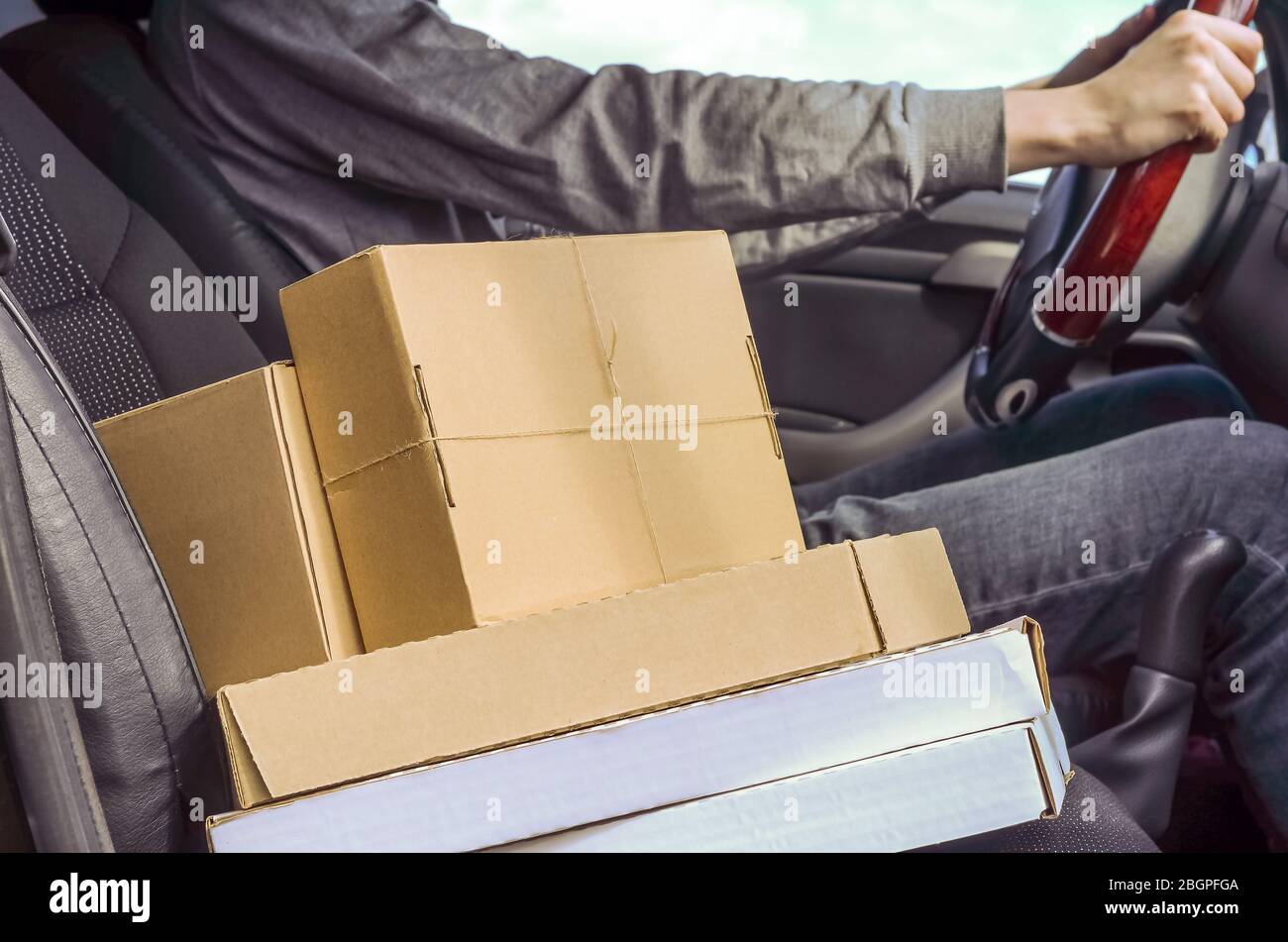 Kurier mit Paketen im Auto. Lieferung von Paketen, Waren, Pizza. Lieferer. Sichere Lieferung während der Quarantäne des Coronavirus. Stockfoto