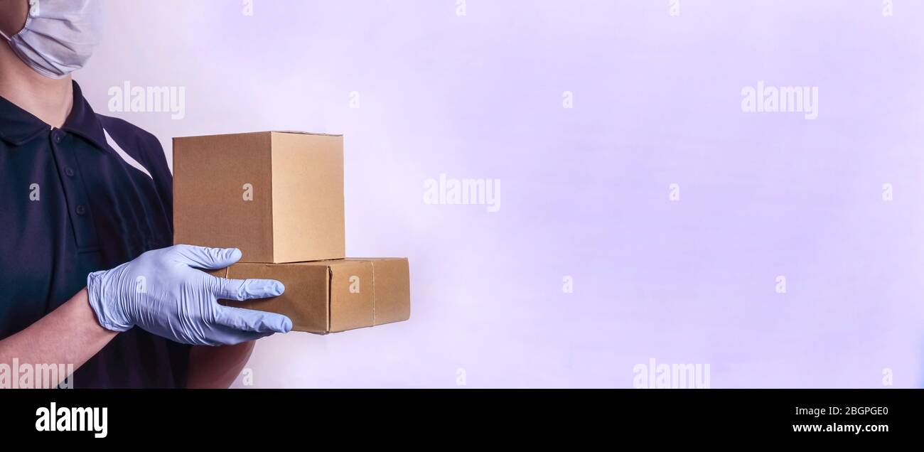 Sichere Lieferung von Lebensmitteln. Ein Kurier in Schutzmaske und Handschuhen liefert Lebensmittel, Pakete und Waren während der Quarantäne des Coronavirus. Hintergrundbanner Stockfoto