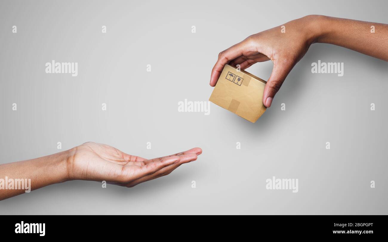 Einfacher Einkauf und Lieferung. Männliche Hand, die kleine Parzelle auf grauem Hintergrund an den Kunden weitergibt, Collage. Panorama Stockfoto