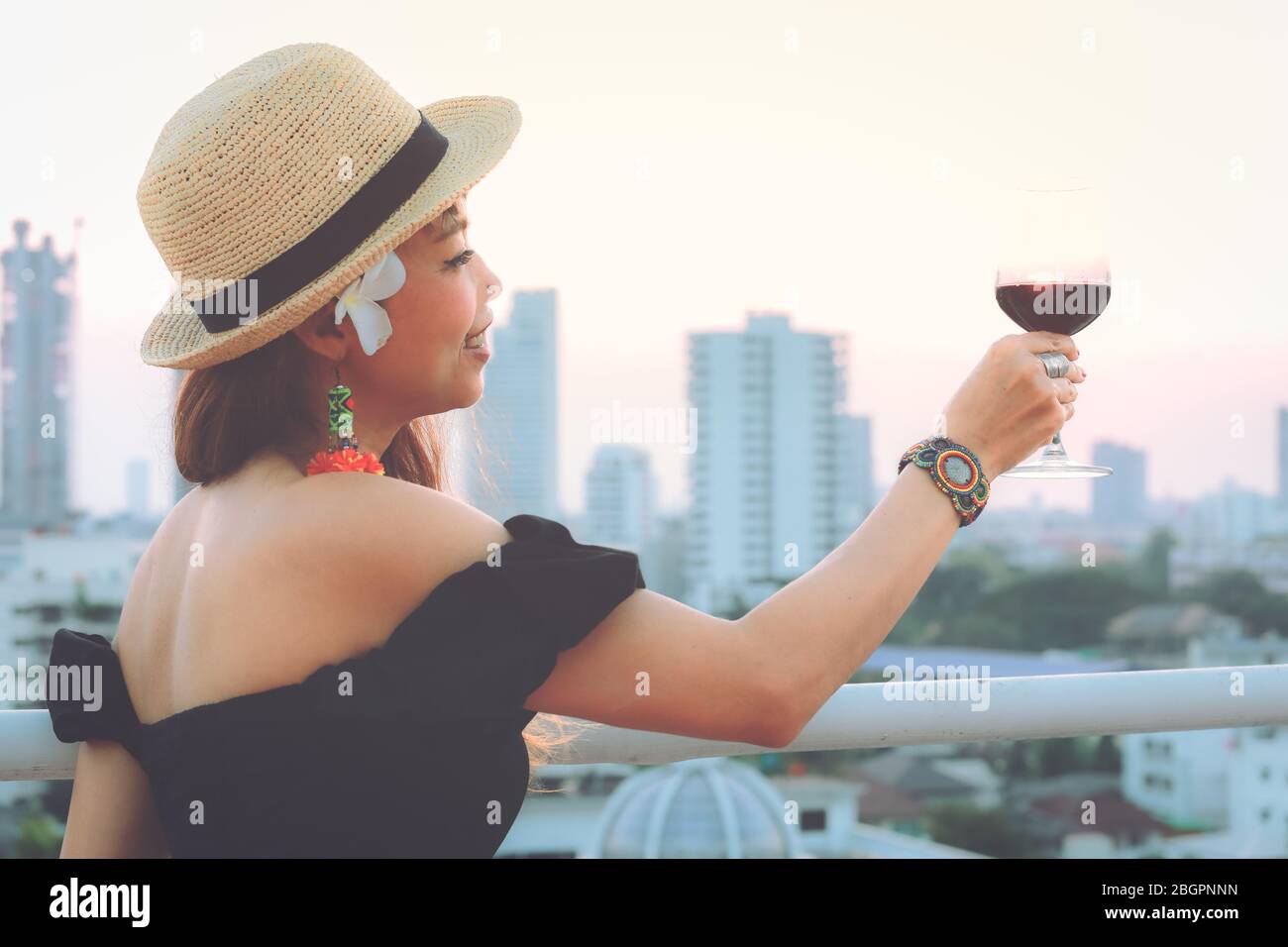 Attraktive junge asiatische Frau Toasting Rotwein Glas auf der Terrasse, Vintage-Stil Stockfoto