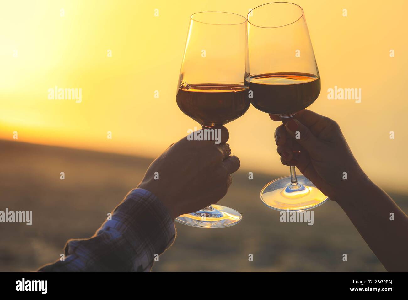 Hände halten Rotweingläser auf Dune von Pyla während des Sonnenuntergangs, Feier Konzept Stockfoto