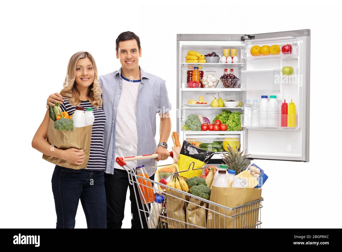 Junges Paar mit einem Einkaufswagen und Kühlschrank mit Lebensmitteln isoliert auf weißem Hintergrund Stockfoto