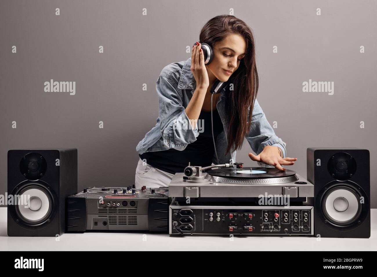 Junge Frau dj Musik auf einem grauen Hintergrund Stockfoto