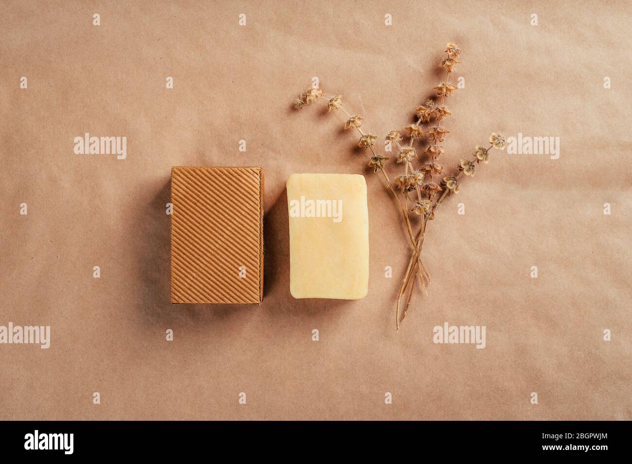 Stück Seife mit Rüschen Karton und trockenen Kräutern auf rustikalem Naturpapier. Gesundheits- und Schönheitskonzept. Stockfoto