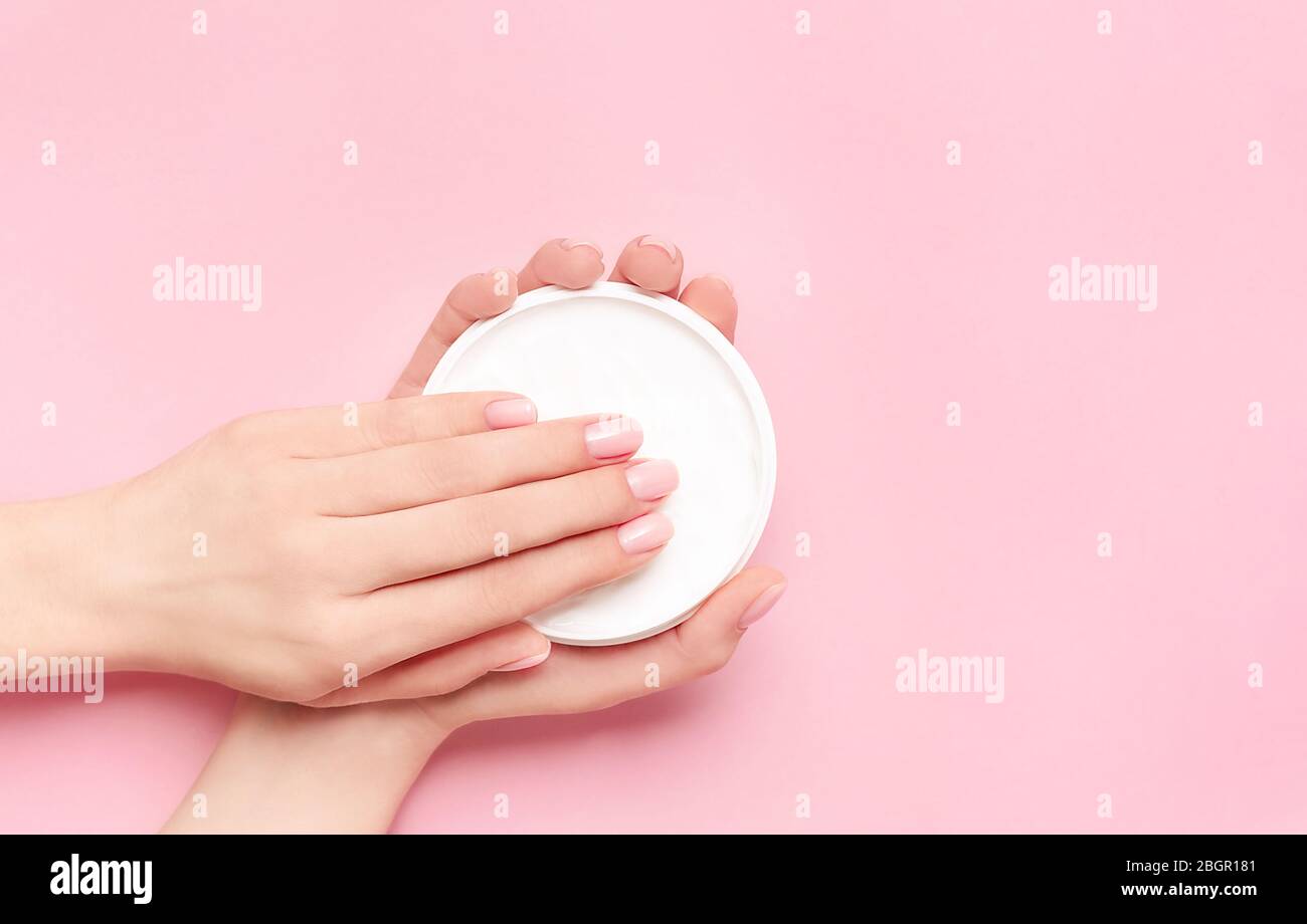 Kreative Bild der Frau feuchtigkeitsspendende ihre Hände mit kosmetischen Creme mit Kopie Raum auf rosa Hintergrund in minimalistischem Stil. Flach Stil. Spa- und b Stockfoto