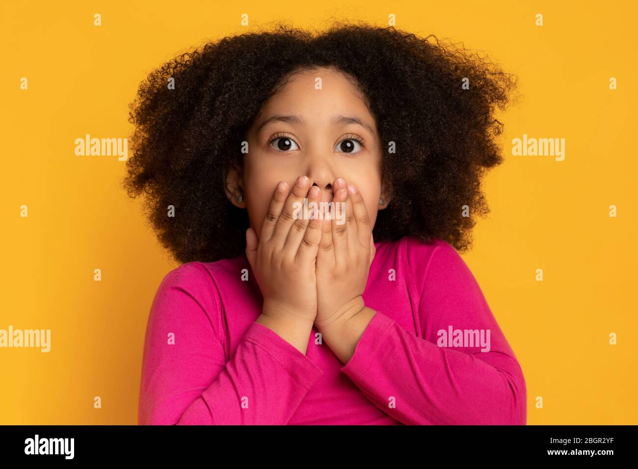 Porträt von erschrocken kleinen schwarzen Mädchen bedeckt Mund mit den Händen Stockfoto