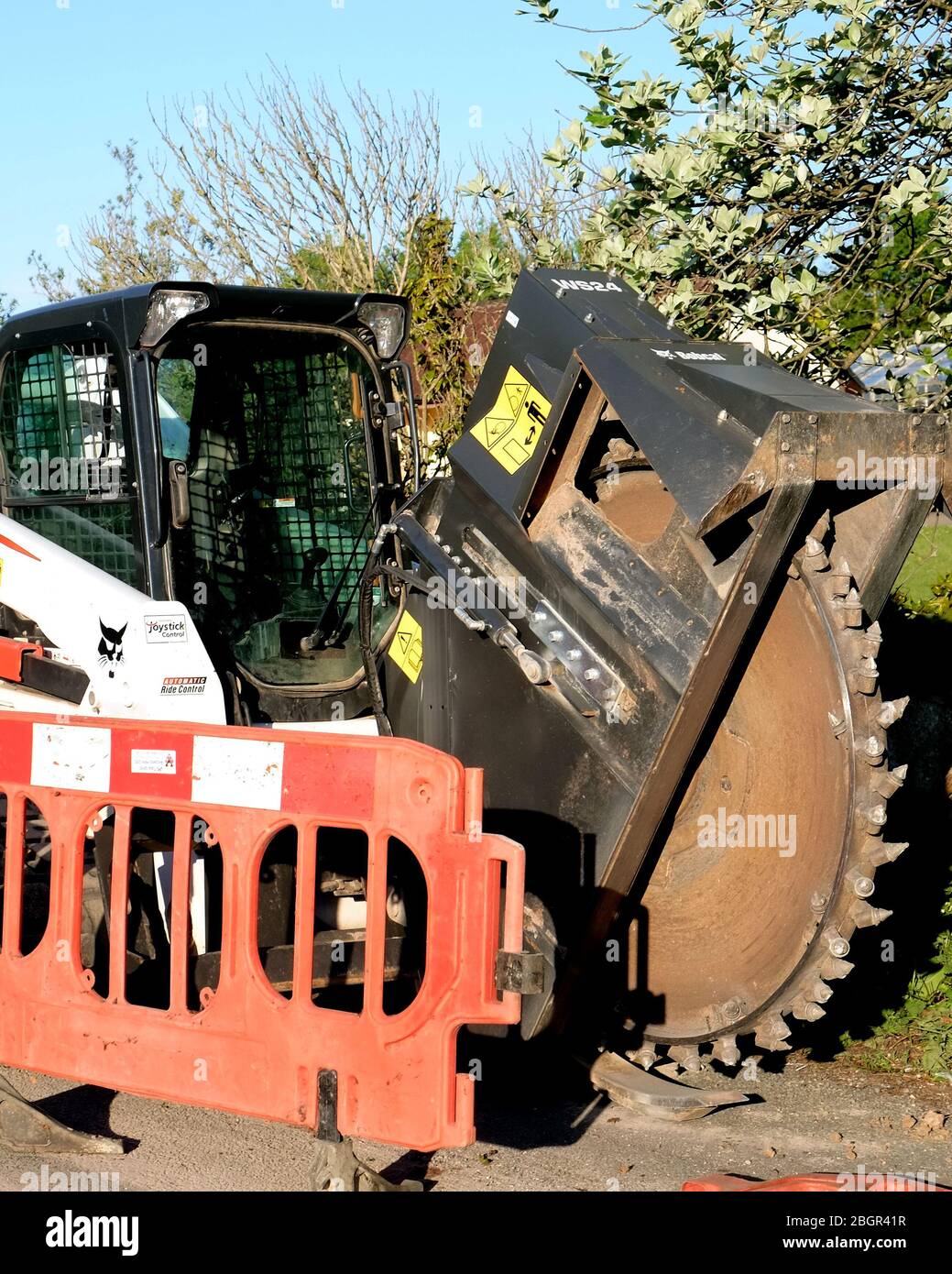 April 2020 - Bobcat-Schlittenlenker-Lader auf Schienen, die mit einem Grabenrad verwendet werden, um Kanäle für Datenkabel im ländlichen Somerset zu verlegen Stockfoto