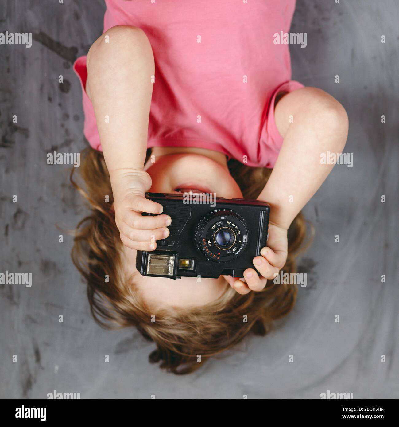 Kleine Mädchen Fotograf mit Kamera lächelnd und machen ein Bild. Draufsicht. Stockfoto