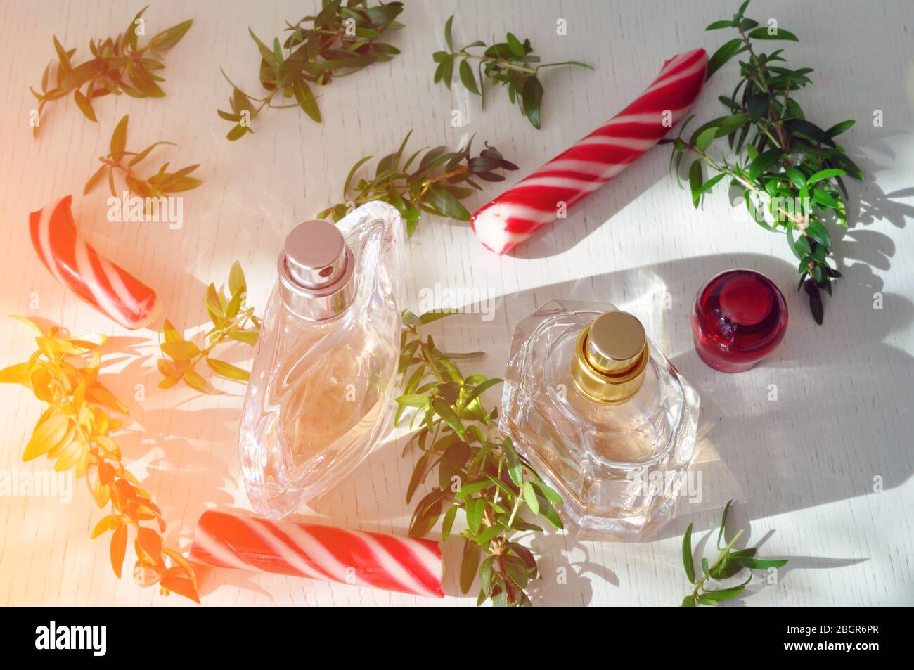 Parfümflaschen auf einer Holzoberfläche mit Karamell und Myrtenzweigen. Ätherisches Öl. Flare Stockfoto