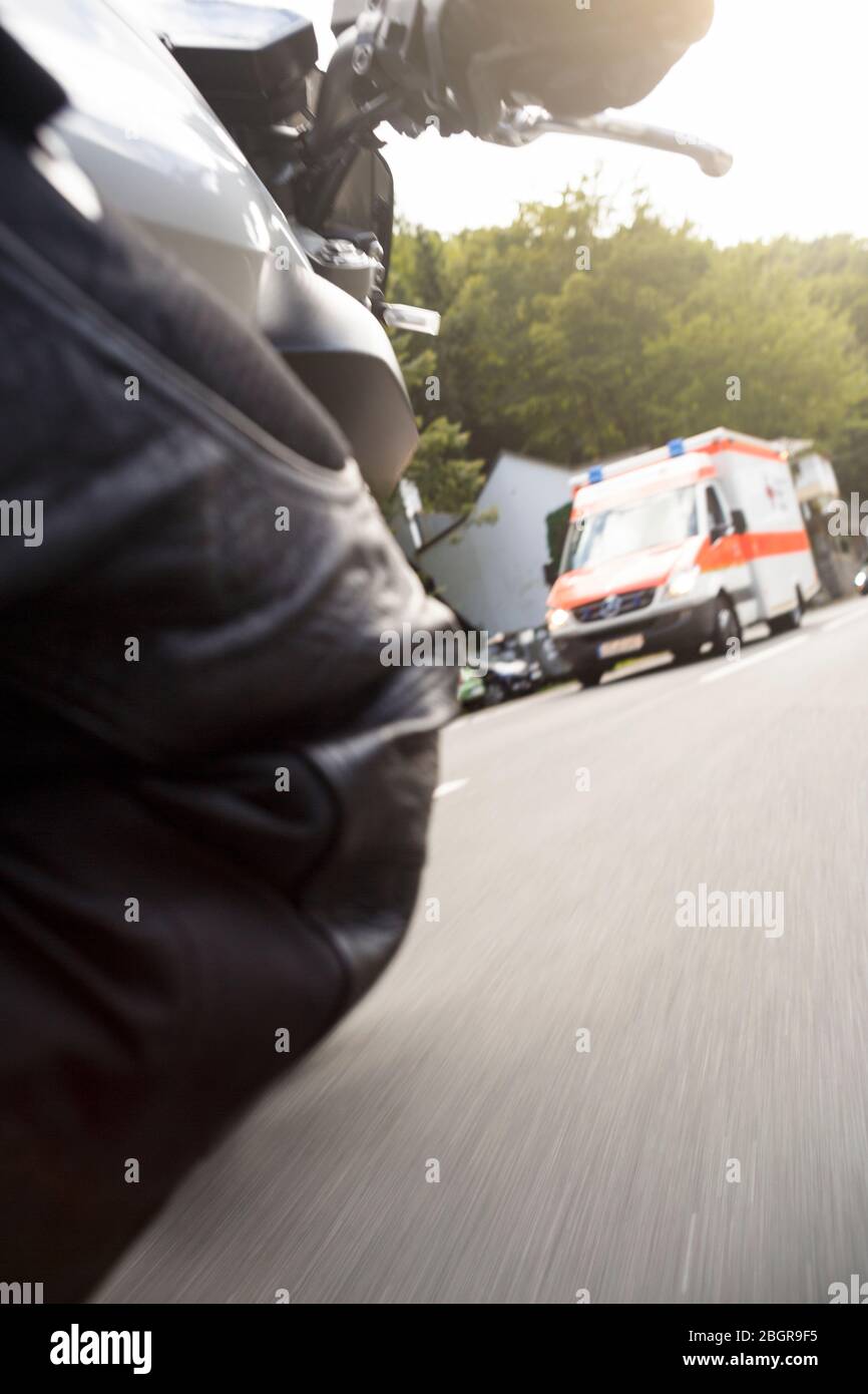 Motorrad Kurve fahren mit Krankenwagen im Hintergrund Stockfoto