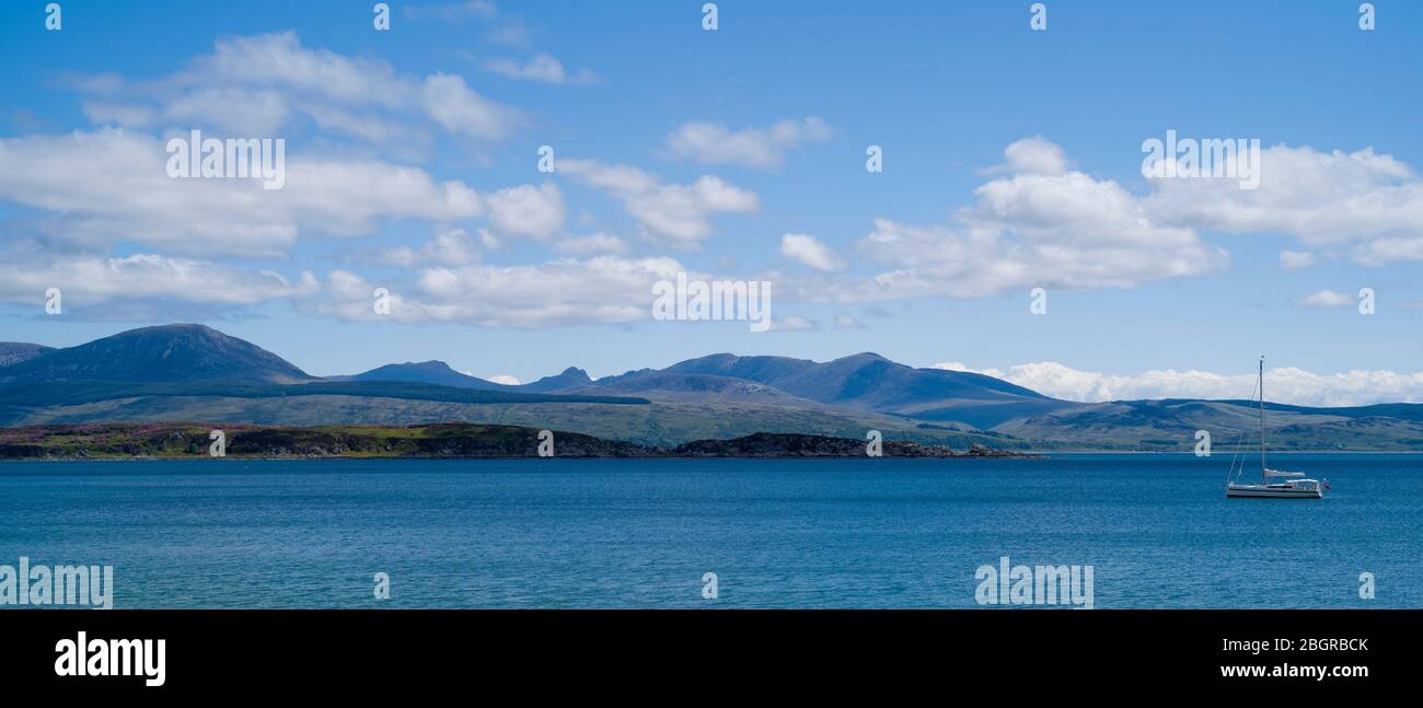 Yacht mit Anker und Isle of Arran in der Ferne von Kintyre, Argyll Küste, Schottland Stockfoto