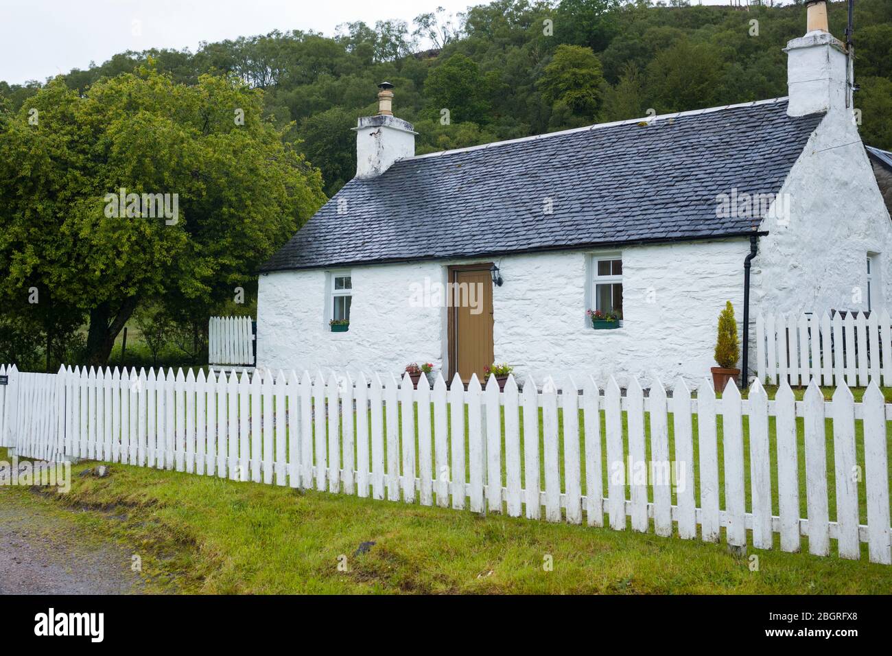 Malerisches traditionelles weiß getünchtes Cottage mit weißem Zaun und gefliestem Dach in Appin, Argyll und Bute, Schottland Stockfoto