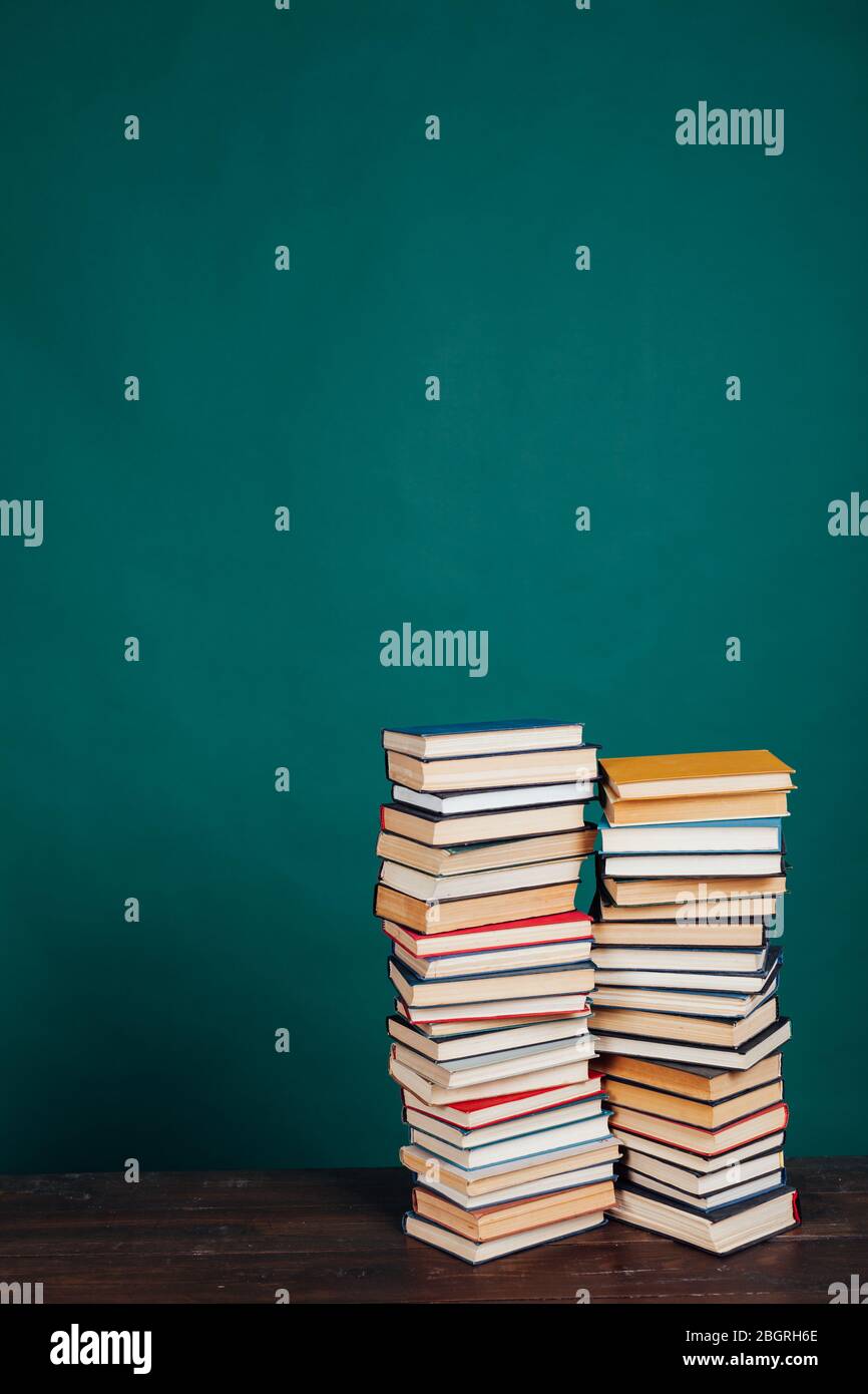 Viele Stapel von Lehrbüchern in der Universitätsbibliothek auf grünem Hintergrund Stockfoto