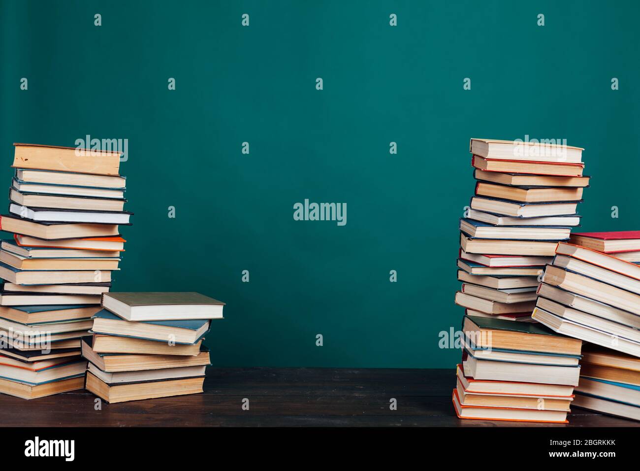 Viele Stapel von Lehrbüchern in der Universitätsbibliothek auf grünem Hintergrund Stockfoto
