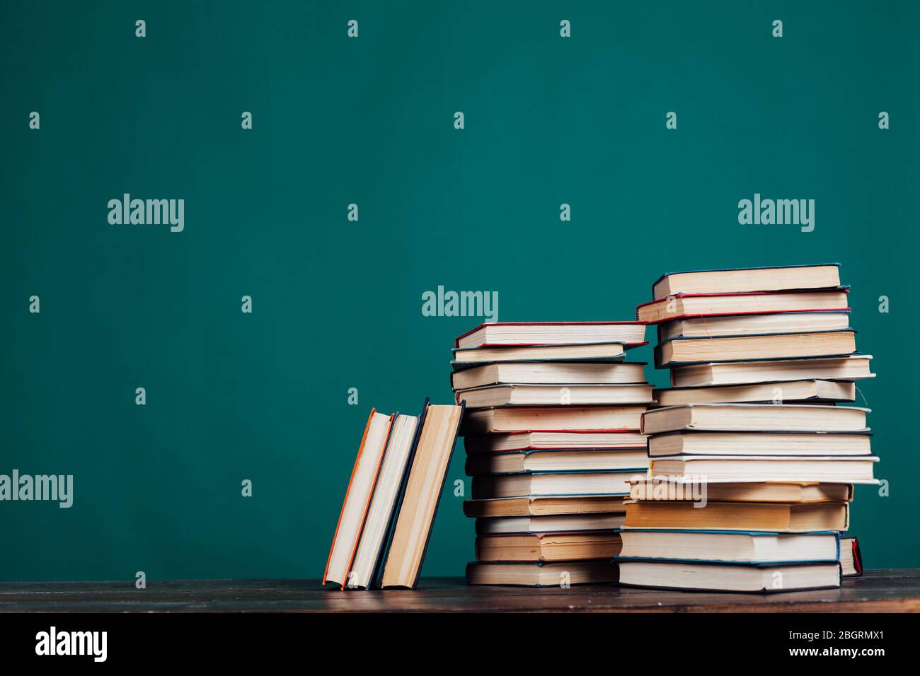 Viele Stapel von Lehrbüchern in der Universitätsbibliothek auf grünem Hintergrund Stockfoto