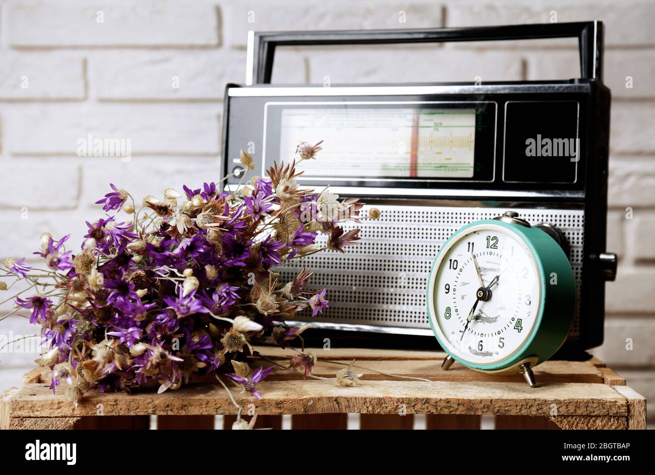 Retro-Radio, Uhr und Blumen auf dem Tisch im Zimmer Stockfoto